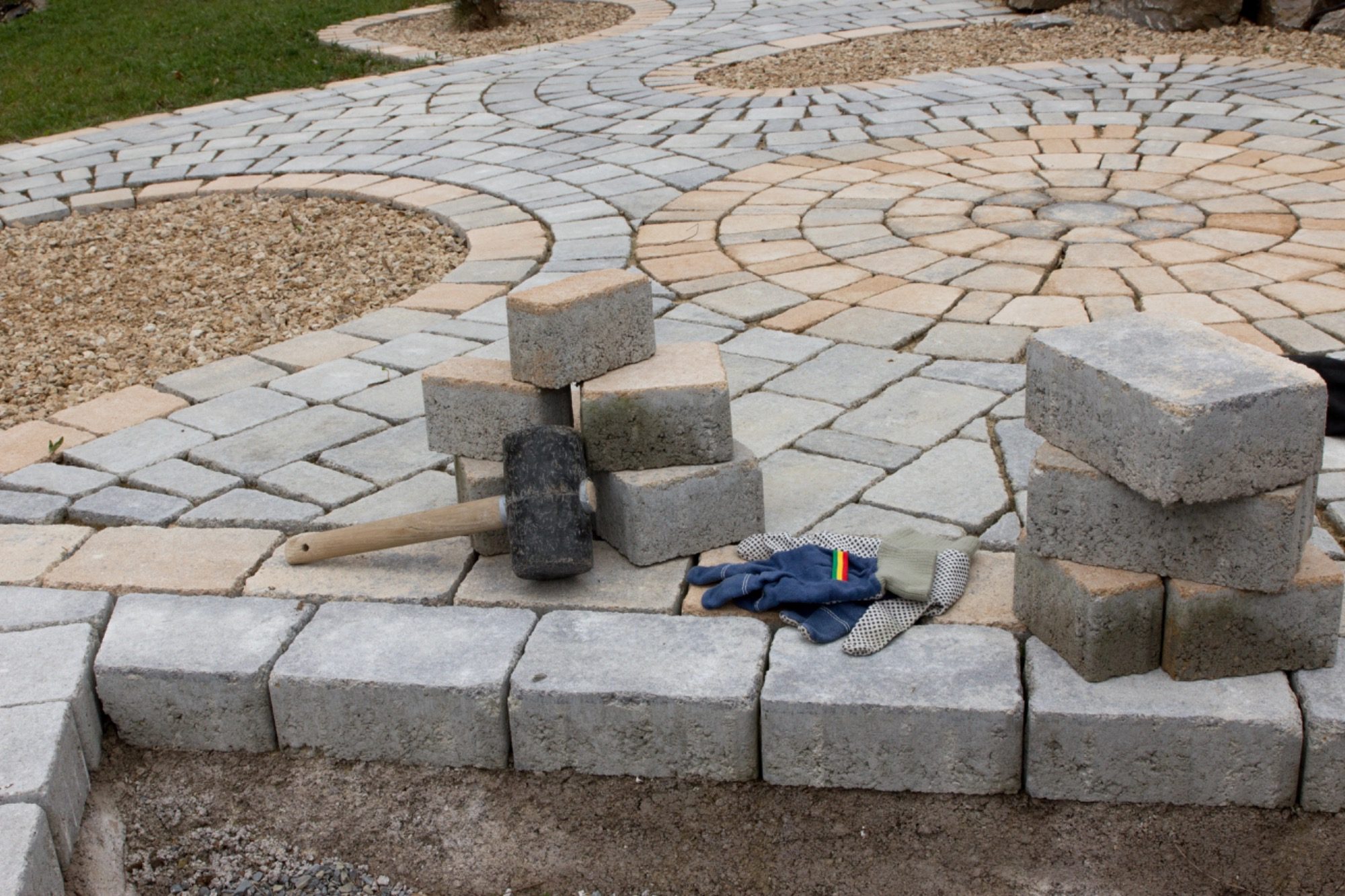 Steine und Werkzeuge auf einem gepflasterten Weg in einem Garten.